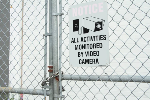 ビデオ カメラによって監視されるすべての活動 黒い印刷物が付いている白い長方形の印および銀のダイヤモンドの塀に対するビデオ カメラのイラスト映像 — ストック写真