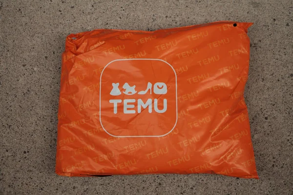 オレンジ色の長方形のバッグパッケージには 舗装セメントに横たわっているロゴが付いています — ストック写真