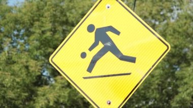 Sarı elmas illüstrasyon yol işareti. Arka planda yeşil üfleme ile top oynayan kişi. Siyah baskı.