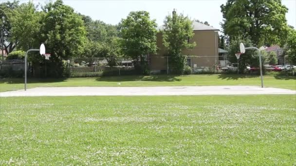 室外公共篮球场被草场包围 场地高耸 全场从侧面射门 — 图库视频影像