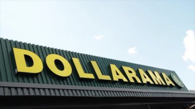 Mağazanın önünde yeşil zemin üzerinde sarı başlıklı gökyüzü olan dollarama logosu işareti