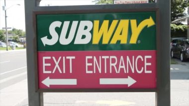 Metro sandviçi restoranının giriş çıkış tabelasında her yeri işaret eden oklar, sıcak yaz gününde sakin bir arka plan.