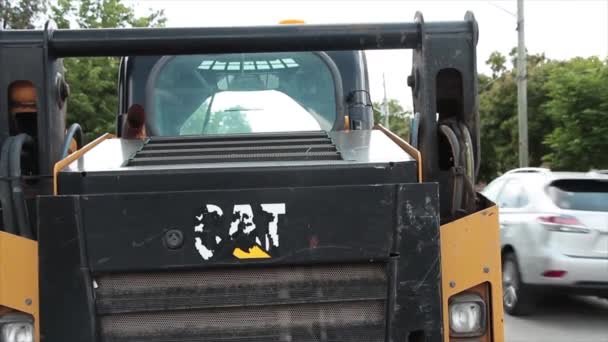 毛毛虫机械后部有褪色的碎屑猫标志 道路后部有白色黄色标志 车辆通过 黑色背景 — 图库视频影像