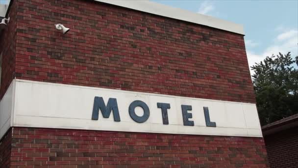 汽车旅馆在汽车旅馆上的签名 用蓝色的木制大写字母与砖墙上的白色相映成趣 后面有树木和天空 — 图库视频影像