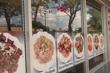 Asya restoranının açık tabelalı pencereleri ve Çin usulü tavuklu pilav, kırmızı biberli tavuk, giriş kapısı, yansıyan gökyüzü ağaçları altında yazılı yemek tabağı resimleri.