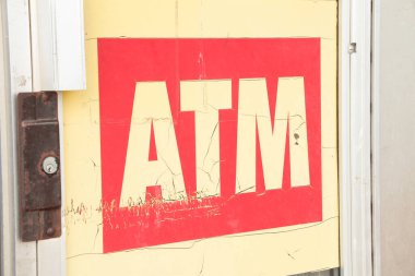 ATM işareti büyük harflerle bej bej beyaz yazılar ve büyük harflerle kırmızı arkaplan