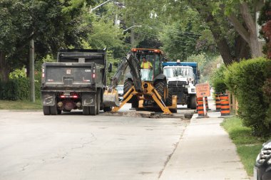 Kazıcı beton kırıcı kepçeci kepçeci kepçeci matkap makinesi çöp kamyonunun yanındaki çöp kamyonunu tamir ediyor. Kepçeyi hafifçe kaldırıyor.