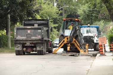 Kazıcı beton kırıcı kazıcı kepçeci kepçeci matkap makinesi çöp kamyonunun yanındaki iskan caddesini onarıyor