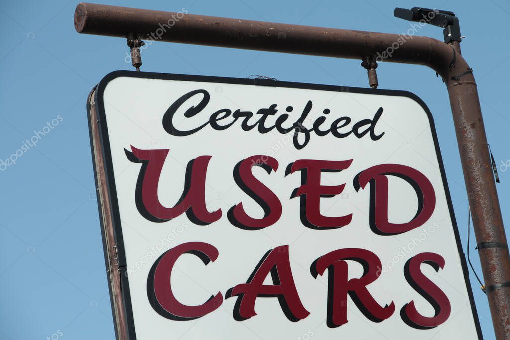 Certified used cars writing caption text sign hanging from metal post in nice writing, burgundy and white with blue sky behind