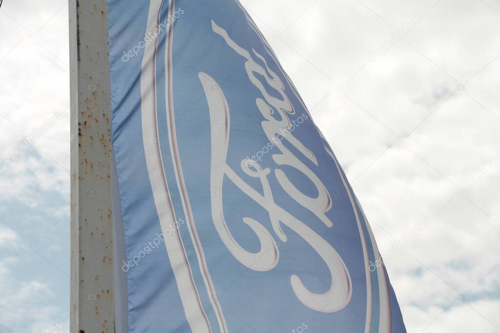 Ford motors flag logo blowing in wind with sky in background, close up with top corner collapsing