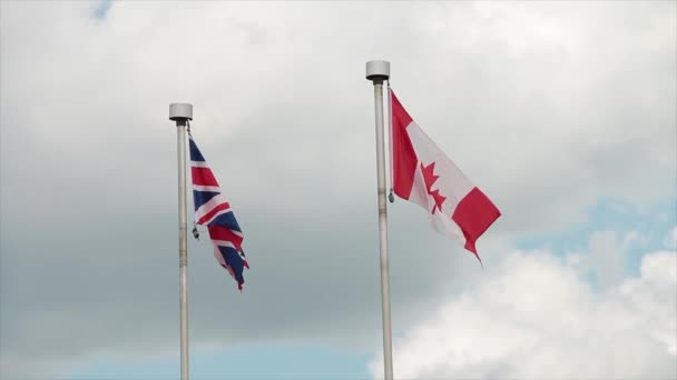 加那底的加拿大国旗和英国的大英帝国国旗挂在旗杆上 迎风轻轻飘扬 云层随风飘扬 公共汽车从前面驶过 — 图库视频影像