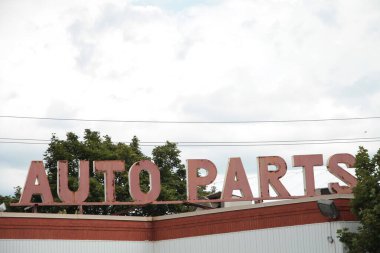 Kelimeleri otomatik parçalar başlık işareti harfleri binanın tepesinden çıkan ağaçlar ve gökyüzü arkasında