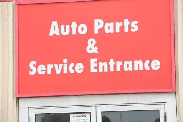 auto parts and service entrance sign on hot summer day, white writing on red background, close up