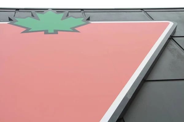 店壁の上の空 緑のメープルリーフの赤い三角形の黒い背景に対するカナダのタイヤのロゴの大きな右 — ストック写真