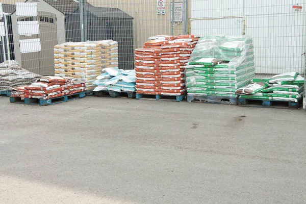 skids palettes of packaged garden soil in parking lot on display for sale next to one another
