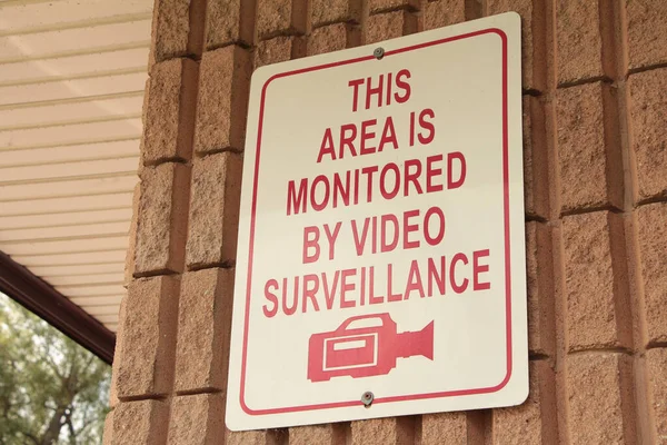 このエリアは ビデオ監視ライティングキャプションテキスト長方形のサインと壁に対するカメラの絵のイラスト 白い背景に赤い書き込みによって監視されています — ストック写真