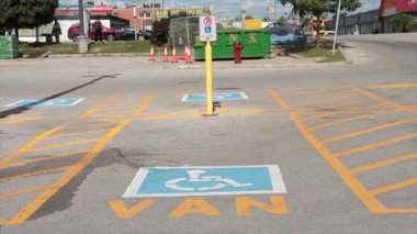 Özürlü simgesinin altında yazılı minibüs engelli park alanı, arka planda geçen trafik araçları