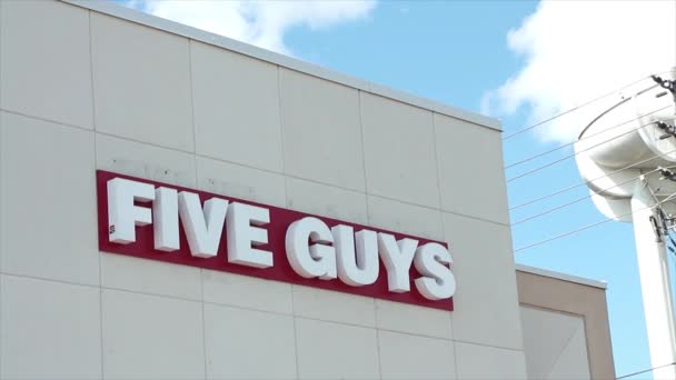 五个男人在水塔旁边的店面墙上写着他们的标志 — 图库视频影像