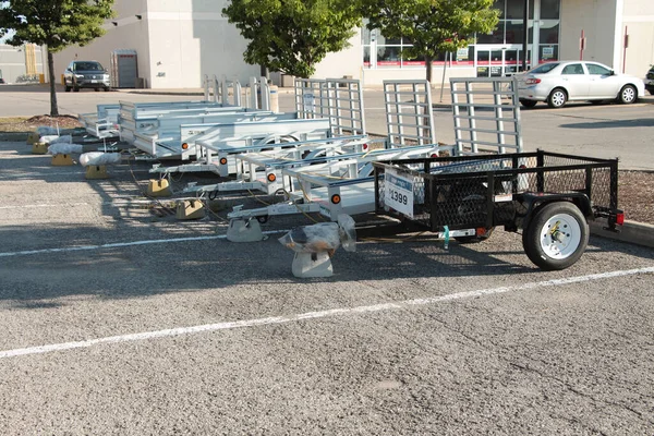 line row of two wheel welder wagon utility trailers outside outdoors on display for sale in parking lot in front of store