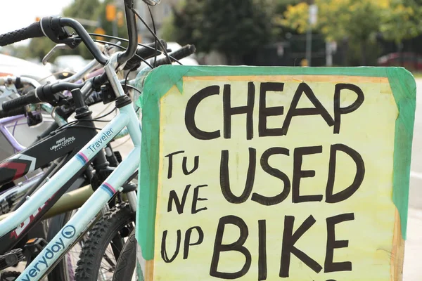 cheap used bike tune up rectangle handwritten in black marker sign with parked bicycles bikes behind it, tight close up