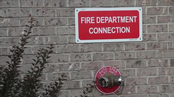 赤い円の自動スプルクの1つのスパウトからの2つのツイン接続が付いているベージュの煉瓦の壁の消防署の関係の印 赤で白 — ストック動画