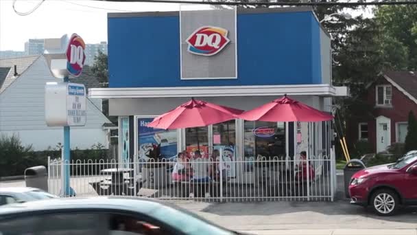夏には傘付きのパティオ付き乳製品のクイーンストアレストラン 車のトラフィックが正面の道路通りに通過 — ストック動画