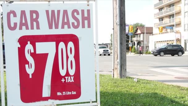 車洗浄 708 7ドルプラス税25リットルのガスサイン広告の横と背後には 明るい空で横断する車両を運転する — ストック動画