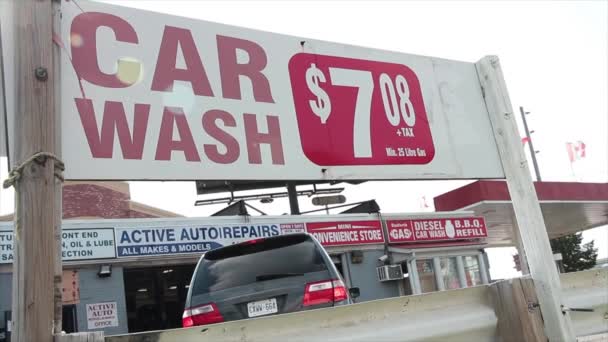 車洗浄 708 7ドルプラス税25リットルのガス横の長方形のサインと車の車が引き離し 別の引っ張って後ろに明るい空と — ストック動画