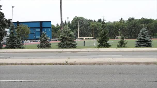 足球场球场的田径运动从马路对面投篮 球门为黄色 球门为白色 球门后为记分板 — 图库视频影像