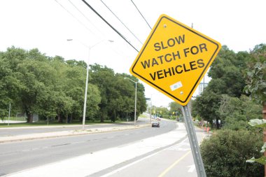 # Yol kaldırımının yanındaki sarı elmas çarpık tabela için yavaş saat #