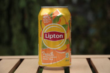 Lipton şeftali, doğal aromalı buzlu çay, açık havada, açık kahverengi masada gazoz, arkası yeşil, kapatın.