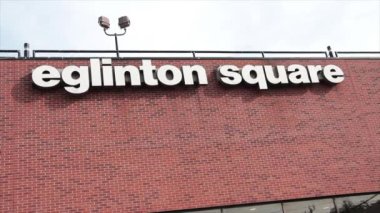 Eglinton Meydanı Alışveriş Merkezi tabelası pencerelerin üstündeki tuğla duvara başlık metni yazıyor