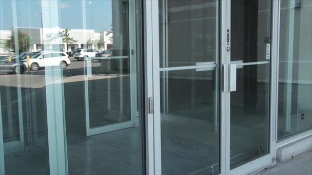 一般玻璃店门及窗前入口 可反映停车场 天空及过往车辆的倒影 — 图库视频影像