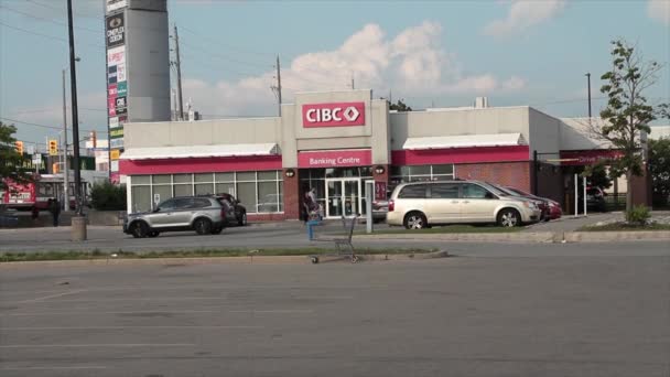 カナダのインペリアル バンク コマーシャル エントランスは 駐車場を前面に置き 民間人が車を運転し 前面と背景と背後にある空を通り抜け ワイドショット — ストック動画