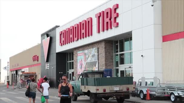 カナダのタイヤ店は前部に駐車し 顧客は看板およびロゴおよび車の通過が付いている出口の店に入ることを歩きます — ストック動画