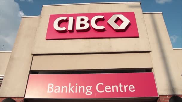 カナダの商業銀行バンキングセンターのロゴマークは 後ろの空の背後にある銀行の玄関の上でサインします — ストック動画