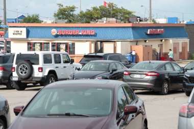 Park yerinde bir sürü arabası olan ve arka planda müşterileri olan Burger King restoranı bayiliği.