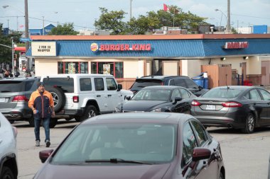 Park yerinde bir sürü arabası olan ve ön planda müşterileri olan Burger King restoranı bayiliği.