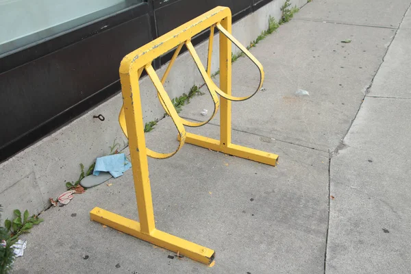 yellow bike bicycle rack lock parking station for parking and locking your bike on sidewalk pavement concrete cement empty with no bikes