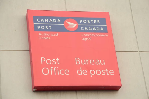 stock image canada post authorized dealer post office square sign mounted on wall, red blue white