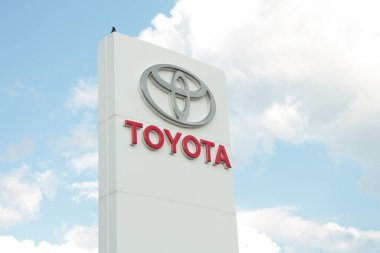 Dışardaki bayiliğin beyaz sütununda, üzerinde kuş resmi olan toyota logosu, geniş açı.