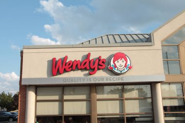 Wendys 'in restoran logosu pencerenin üstündeki inşaat dükkanında açık havada açık havada, arkasında gökyüzü bulutları olan, orta ölçekli