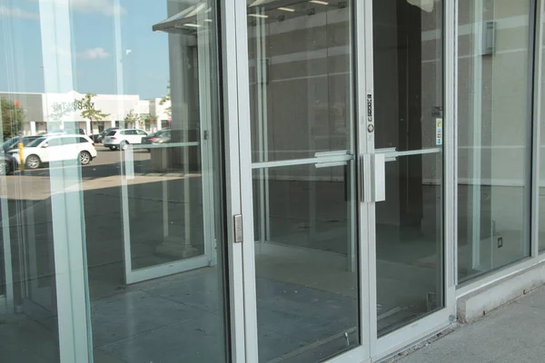 generic glass store doors and windows front entrance with reflection of parking lot and sky
