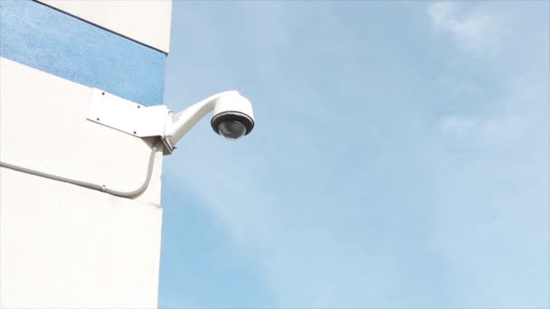 白と黒の背後にある青い空と夏の昼間の建物の壁のコーナーに取付けられた丸い角度の保証カメラ — ストック動画