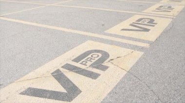 Üç vip pro yazma başlığı yazı yazma yeri park yeri park yerlerinin yanı başındaki park yeri dışarıdaki açık hava altında sarı ve siyah güneş ışığı altında.