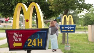 McDonalds yazları girişteki direklerde, biri diğerinin önünde genç bir erkek ve dişinin McDonalds dondurması yiyip arka planda içki içtiği ve tabelalarda yürüyüp gittiği yazılıydı.