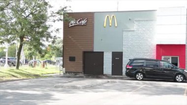 McDonalds Restoran Binası Logo ve McKafe 'nin penceresinden geçip yaz gündüz vakti araç arabasıyla sipariş almak için pencereye yanaşıyor.