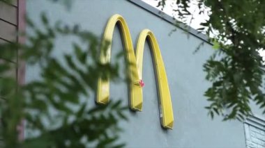 McDonalds 'ın kemeri, ön planda dallar uçuşan dış taraftaki restoran duvarında sarı yay m logosu.