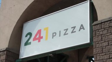 241 pizza restoranı dikdörtgen tabela logosu. Yazın kemer yayı altında. Dışarıda bulutların arkasından parlak güneş çıkıyor ve üzerinde parlıyor.