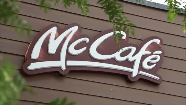 Mccafe マクドナルドのロゴ レストランの建物の側面の茶色の壁 木の枝の葉は外の前景の外側で吹く 閉じます — ストック動画